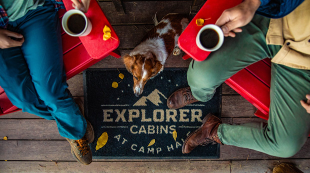 Two guests relaxing with their dog at the Explorer Cabins at Camp Hale